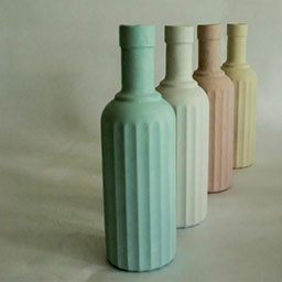 collection of 3D long pastel vessels in shades of pastel green, white, pink and yellow in a row, all with long rectangular textual features.