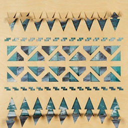 blue triangular and woven rectangular patterns, laser cut onto wooden board.