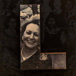 black and white photo in the letter form L, woman wearing pearl necklace smiling.
