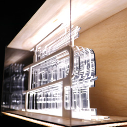 3D geometric acrylic model, curved features in a glass case with wooden back under LED lights.