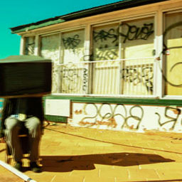 figure of man sitting on chair, TV on head, in front of building detailed with graffiti, yellow tones.
