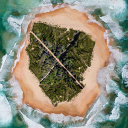 circular aerial landscape, greenery in the centre, sand surrounding in a large 'X' with a sea border, waves crashing.