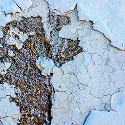 close-up of eroded paint stripping off wall.