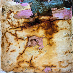 eroding paint, rusted colour and pink on a wooden surface.