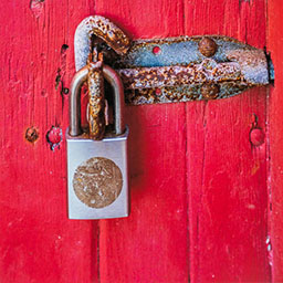 bright pink painted wooden door with rusted padlock screwed in.