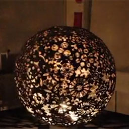 large metal sphere with patterned cut-outs, lit on the inside. 