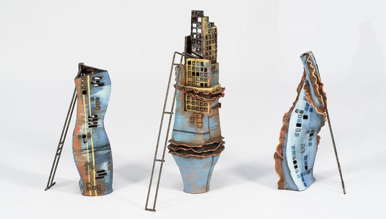 three individual sculptures of abstract high rise buildings in construction, in blues, yellows and with rusty features.