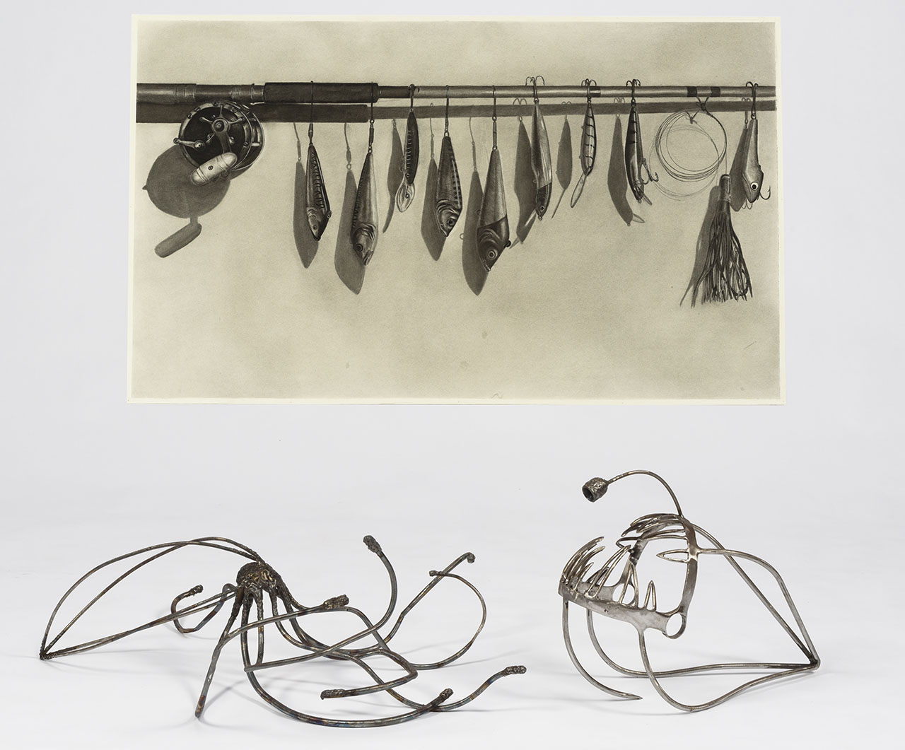horizontal fishing rod with multiple fish shaped lures hanging down and two abstract metal sea creature sculptures.