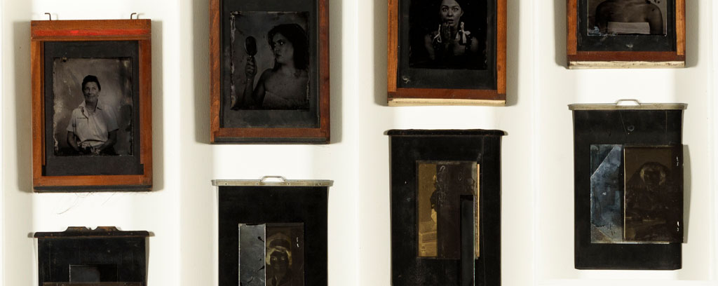 eight long white panels in one row, each with orange frame black and white portrait and antique metal box on a large black background. 