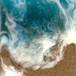 aerial photograph of waves crashing into the sand
