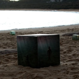 large cube sculpture sitting on sand at the beach