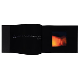 Book of photography with black pages, white writing and bright orange image