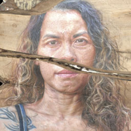 womans face painted onto a textured slab of wood