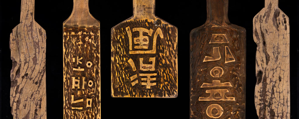Collection of traditional Japanese ceramic vessels and wooden paddles with calligraphic characters engraved on the surface