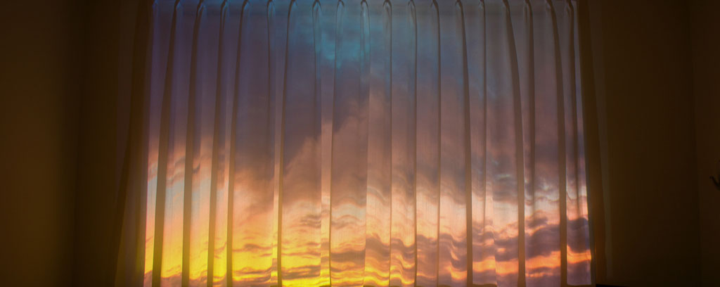 six photographs of colourful sky landscapes viewed through windows with curtains